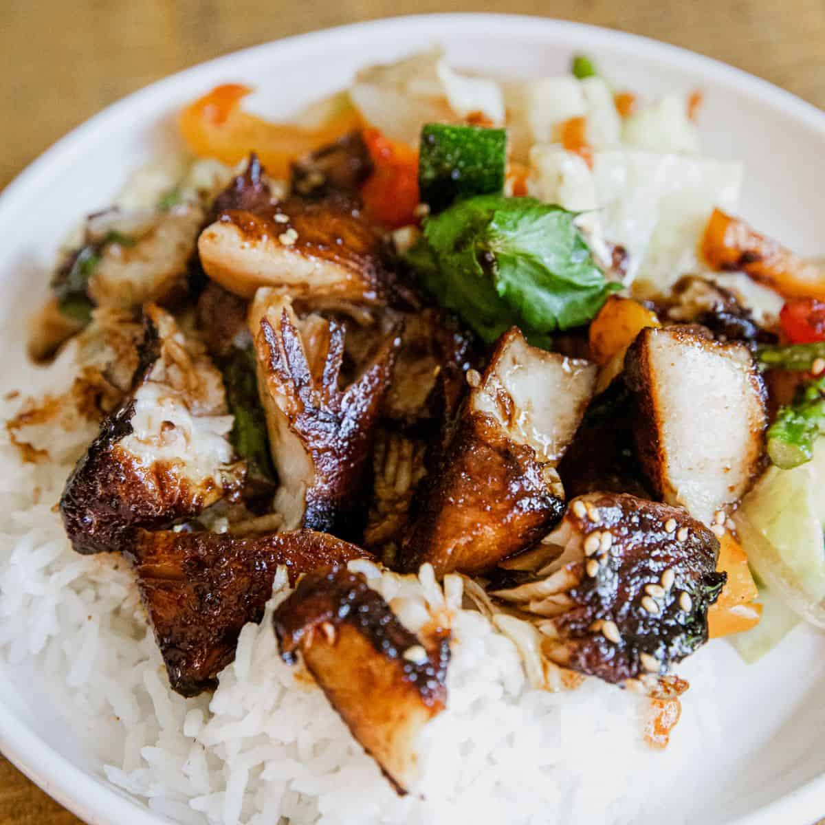 Grilled chicken served with rice and mixed vegetables on a white plate.