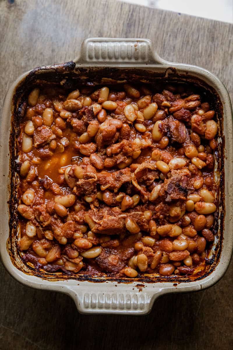 Baked beef and bean casserole in a white ceramic dish, topped with melted cheese.