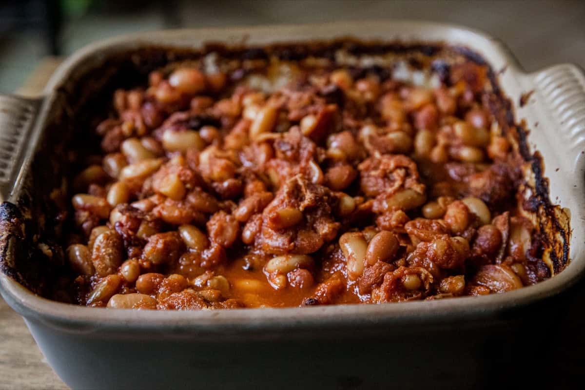 Baked bean casserole in a ceramic dish with a rich tomato sauce.