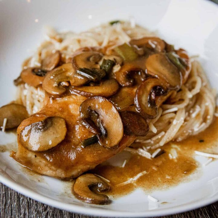 Delicious creamy mushroom chicken served with rice and gravy on a white plate.