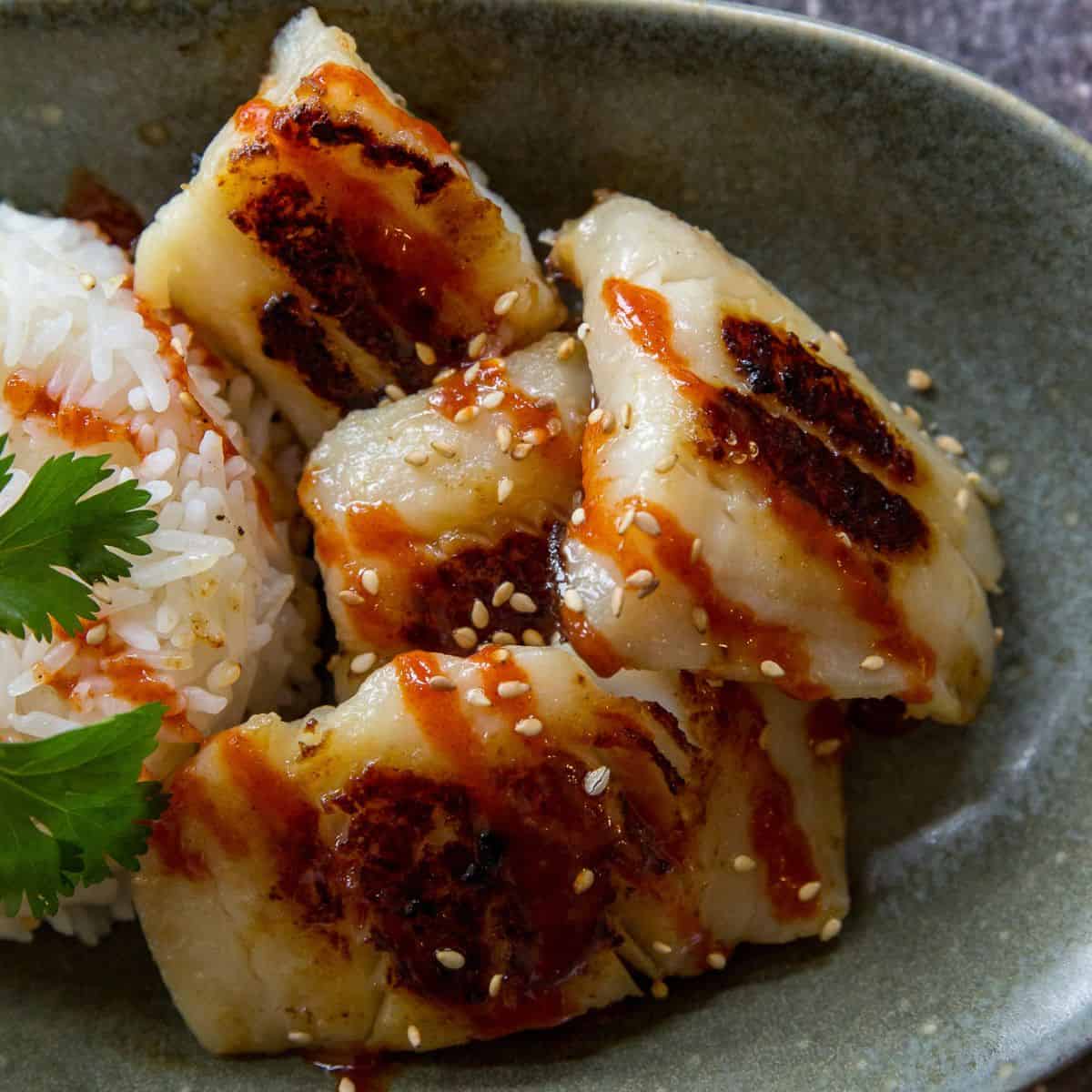 Grilled chicken dumplings served with rice and sesame seeds in a bowl.
