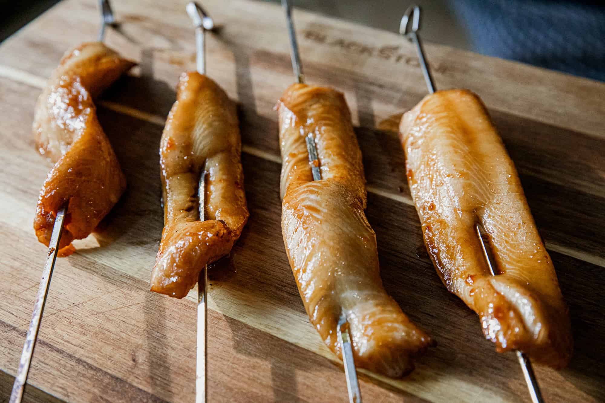 Grilled chicken skewers with a glazed finish, served on a wooden board for a delicious meal. Perfect.