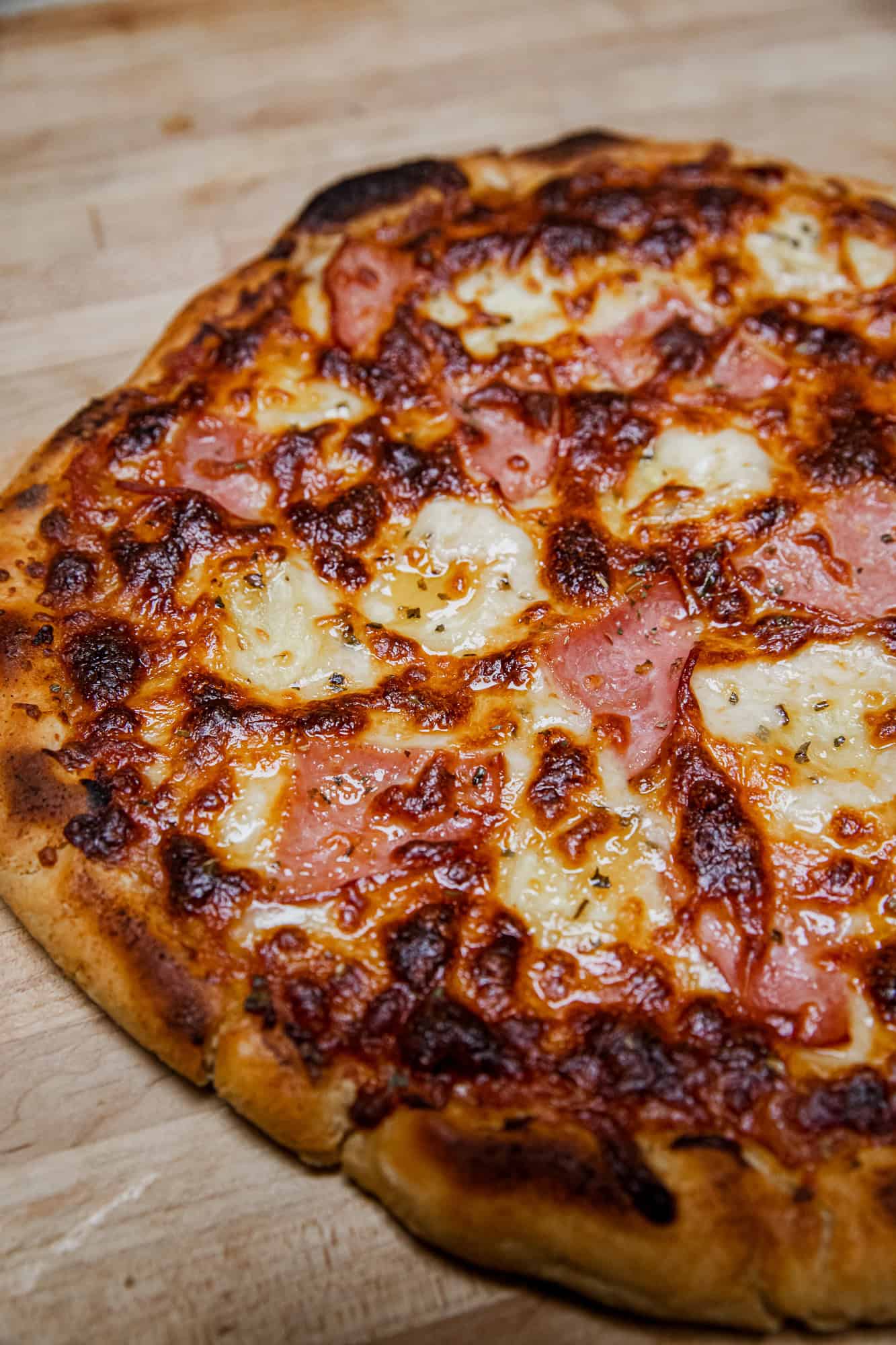 Close-up of a Hawaiian pizza with ham, pineapple, and melted cheese.