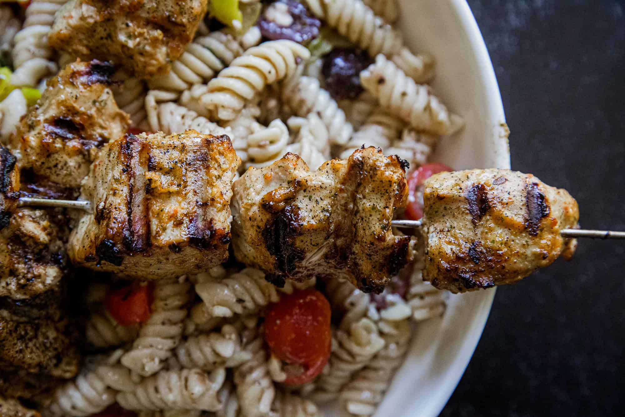 Juicy grilled jerk chicken skewers served over pasta with vegetables.