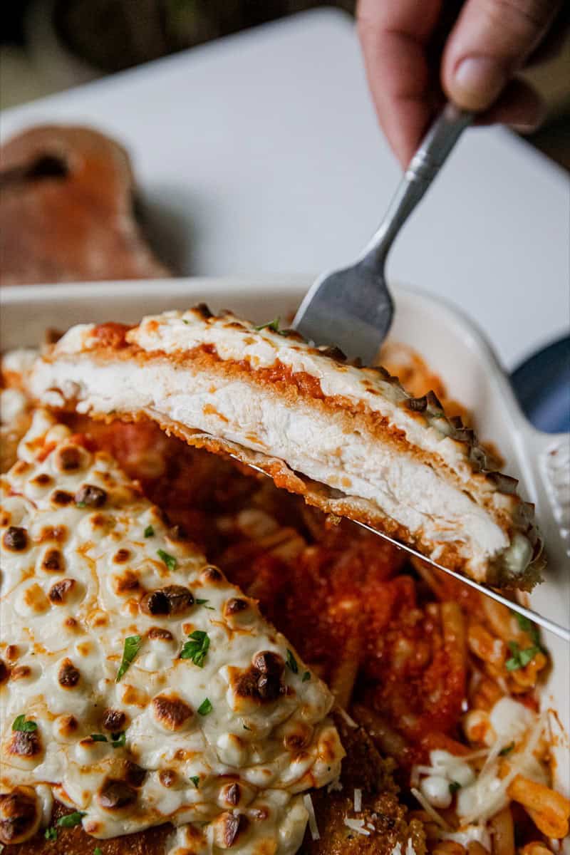 Close-up of a slice of chicken parmesan with melted cheese and tomato sauce.