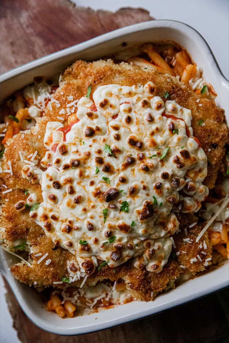 Close-up of Chicken Parmesan with melted cheese and pasta.