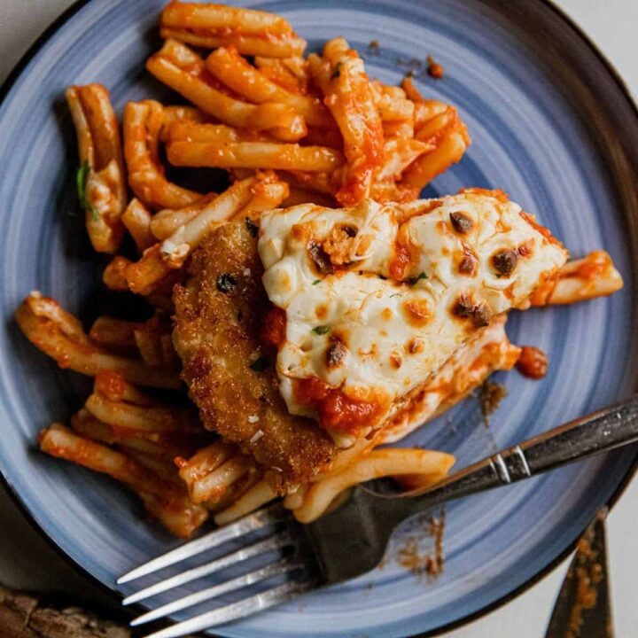Chicken Parmesan served with spaghetti and marinara sauce on a blue plate.