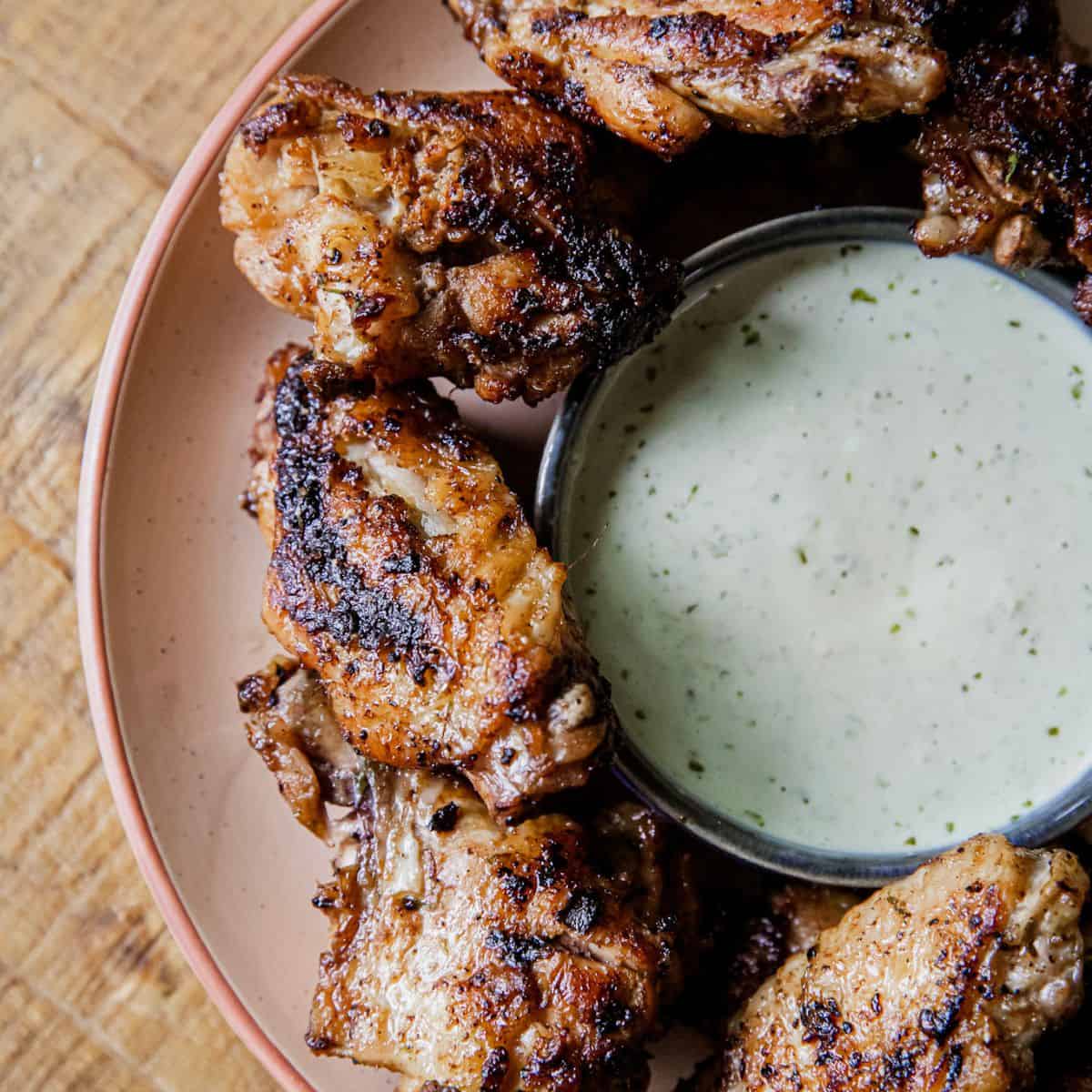 Grilled chicken wings with dipping sauce for tailgating.
