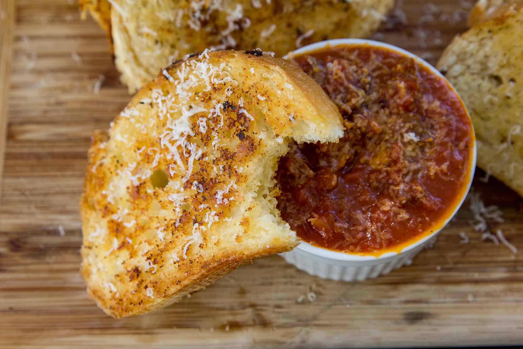 Golden garlic bread served with a side of marinara sauce for dipping.