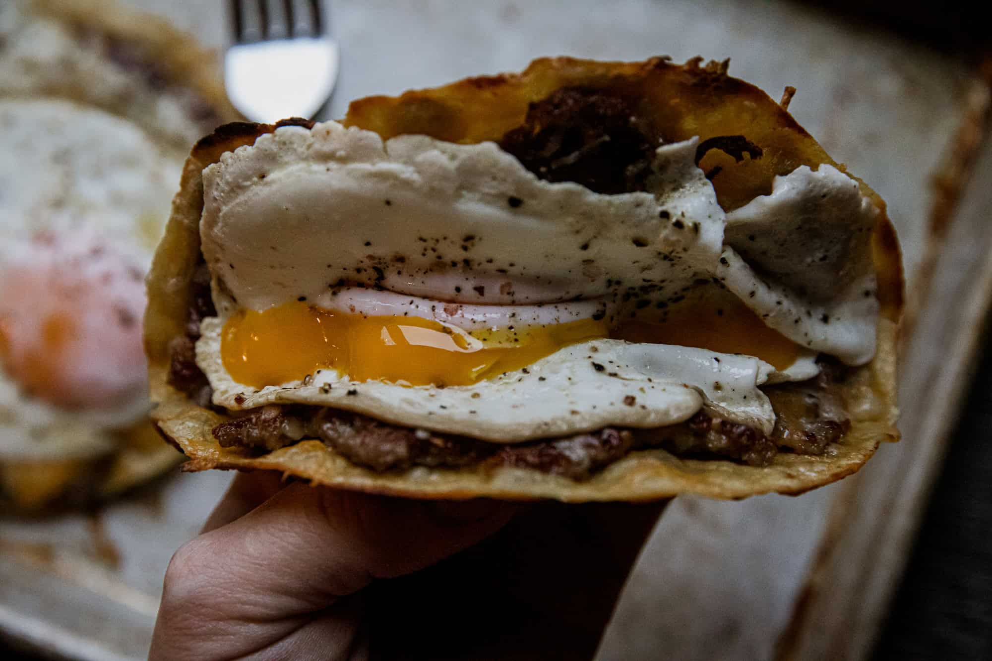 Close-up of a breakfast taco with egg, beef, and sour cream filling.