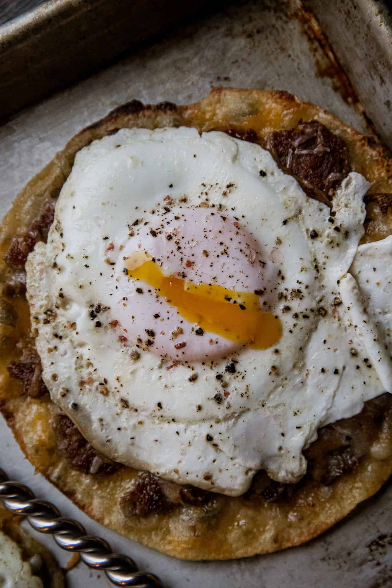 Close-up of breakfast taco with fried egg, beef, and crispy tortilla.