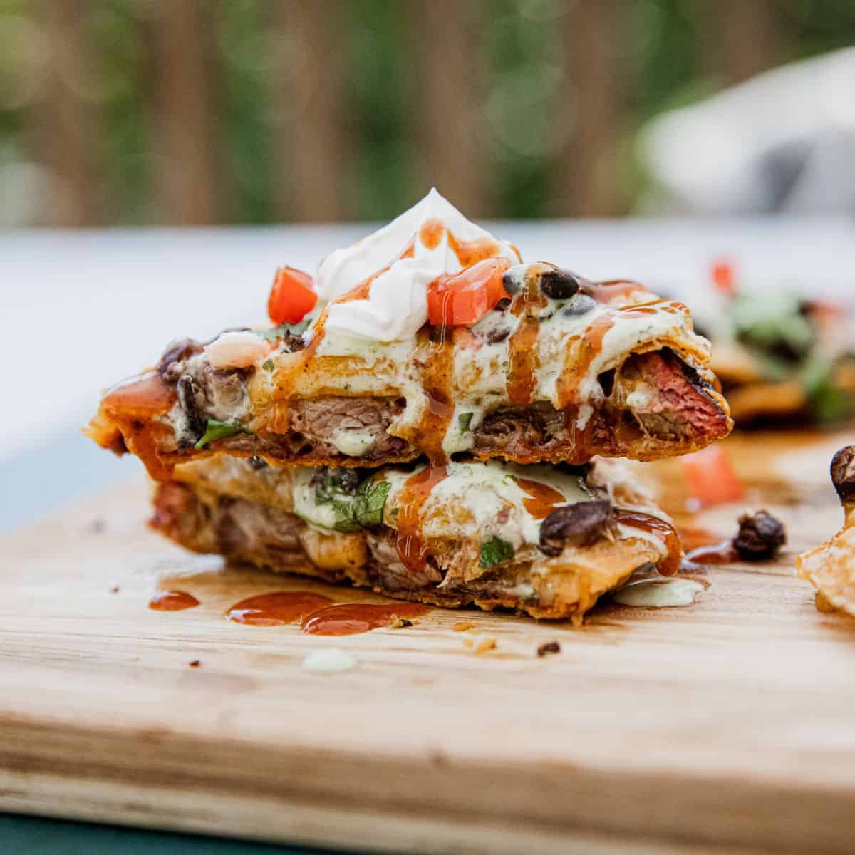 Delicious loaded nachos with cheese, beans, and toppings on a wooden board.