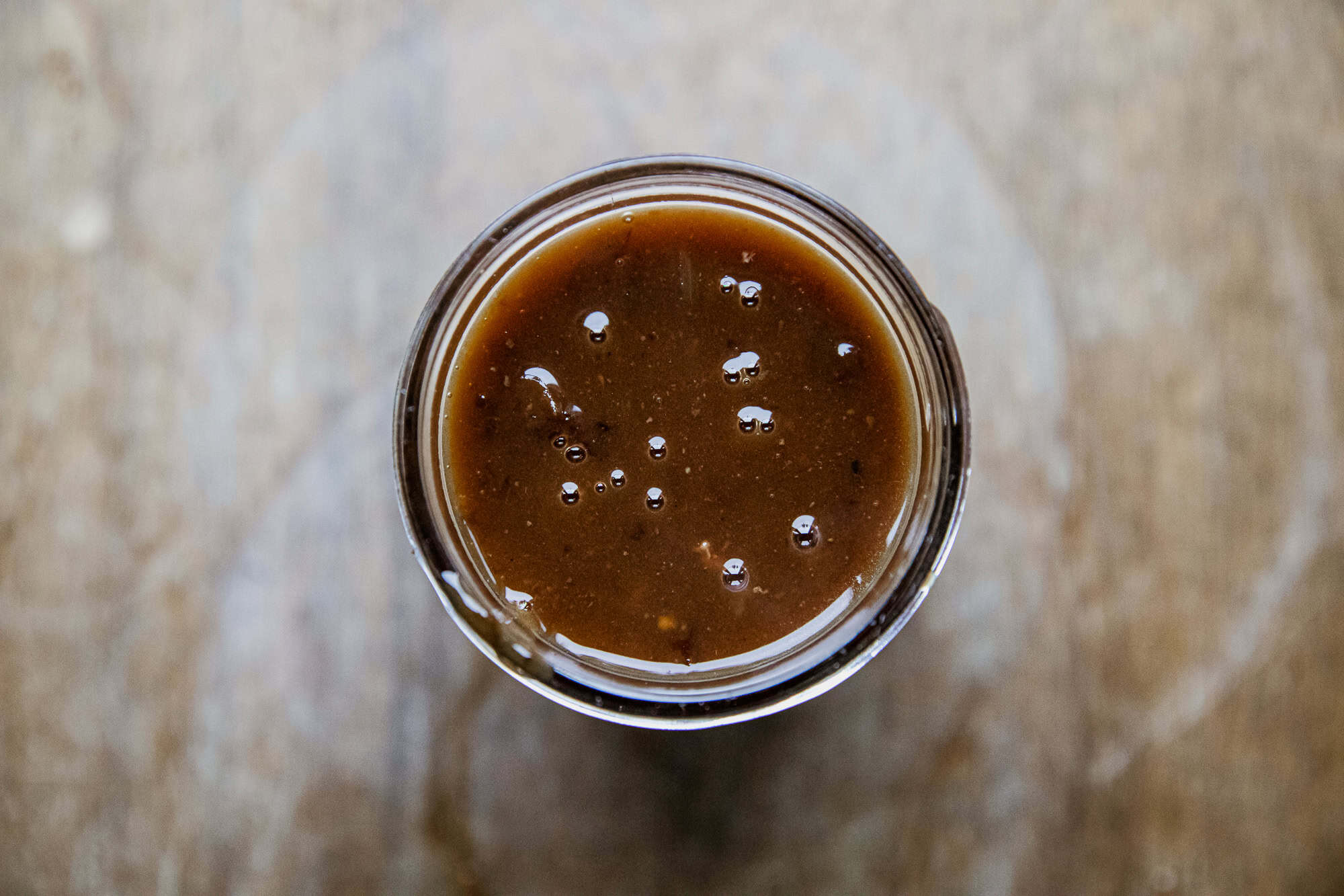 Close-up of beef protein gravy in a glass on a wooden surface.