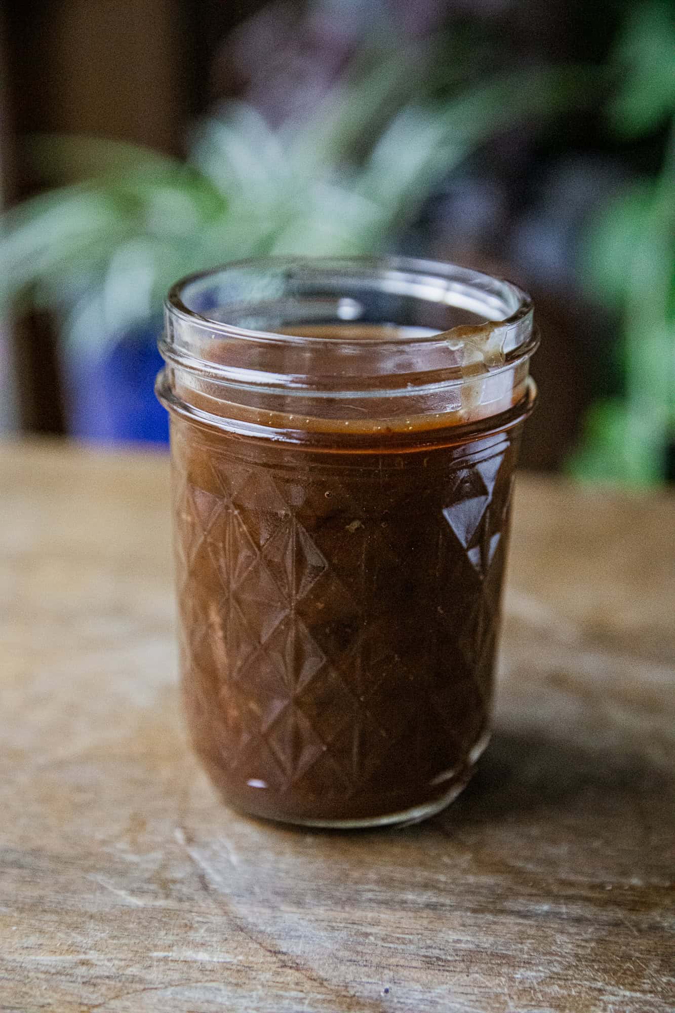 Glass jar filled with rich beef protein gravy on wooden surface.