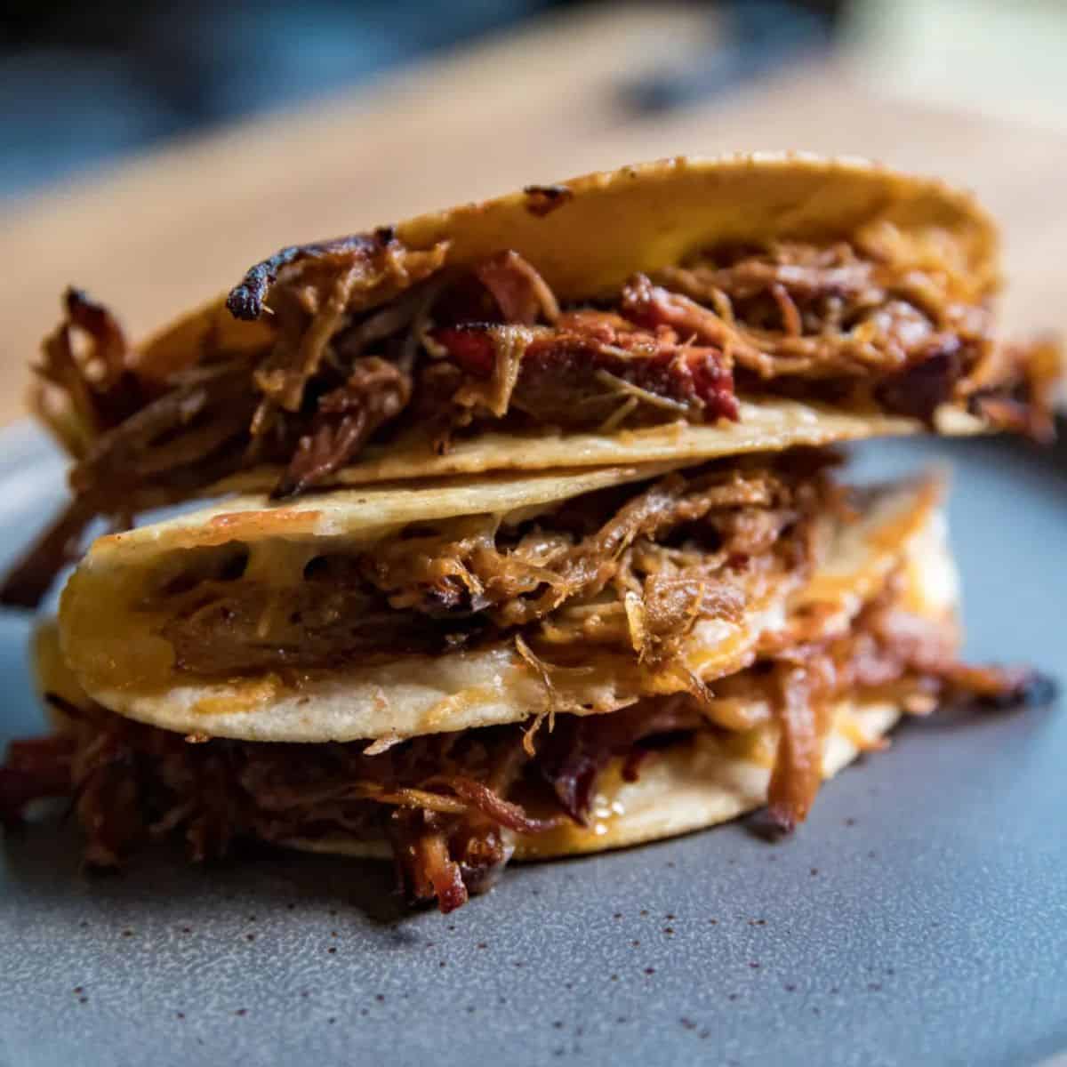 Close-up of pulled pork tacos on a blackstone griddle for tailgating.