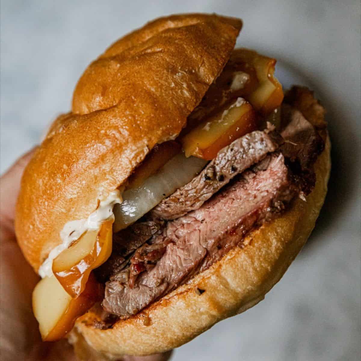 Delicious steak sandwich with melted cheese and toppings on a bun.