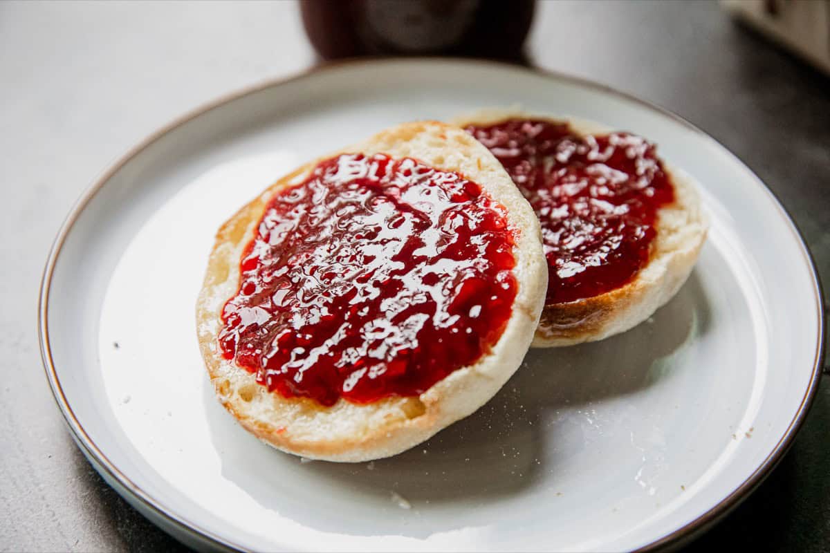 Close-up of toast with fresh tayberry jam on a white plate.
