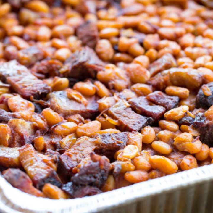 Smoked baked beans with chopped brisket in a foil pan.