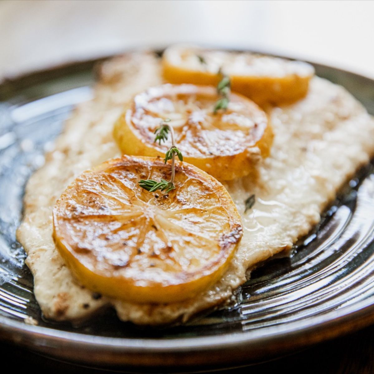 Fish fillets cooking on a Blackstone griddle with lemon.