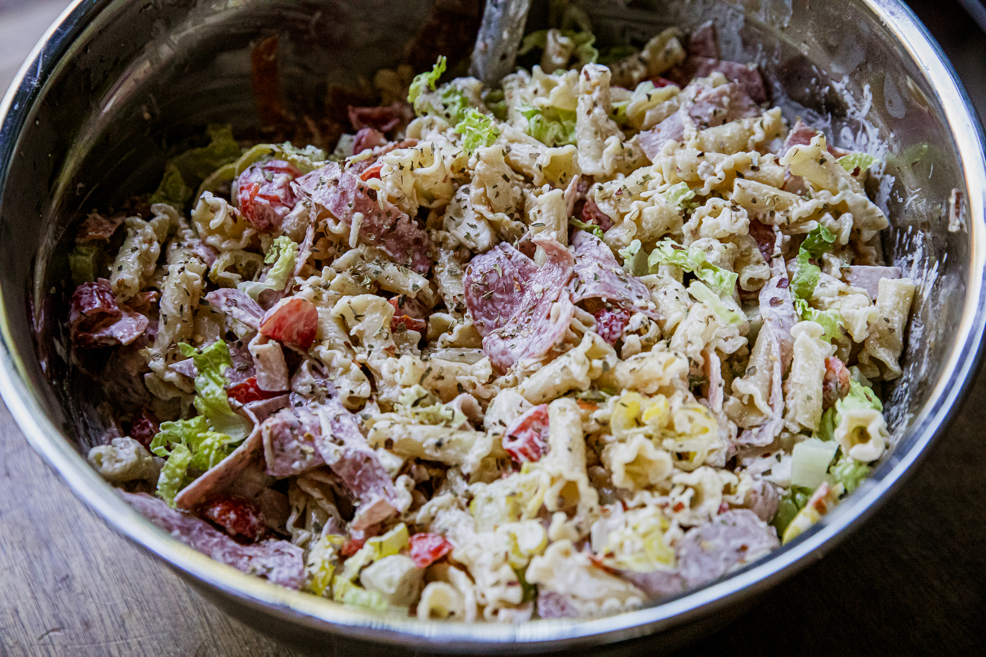 Close-up of Italian grinder pasta salad with meats, cheese, and vegetables in a bowl.