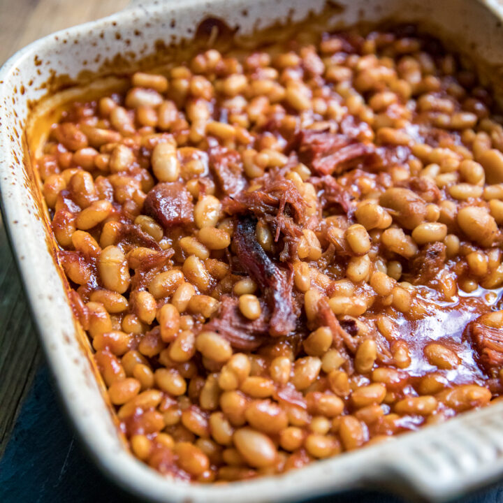 Smoked baked beans loaded with pulled pork in a foil pan.