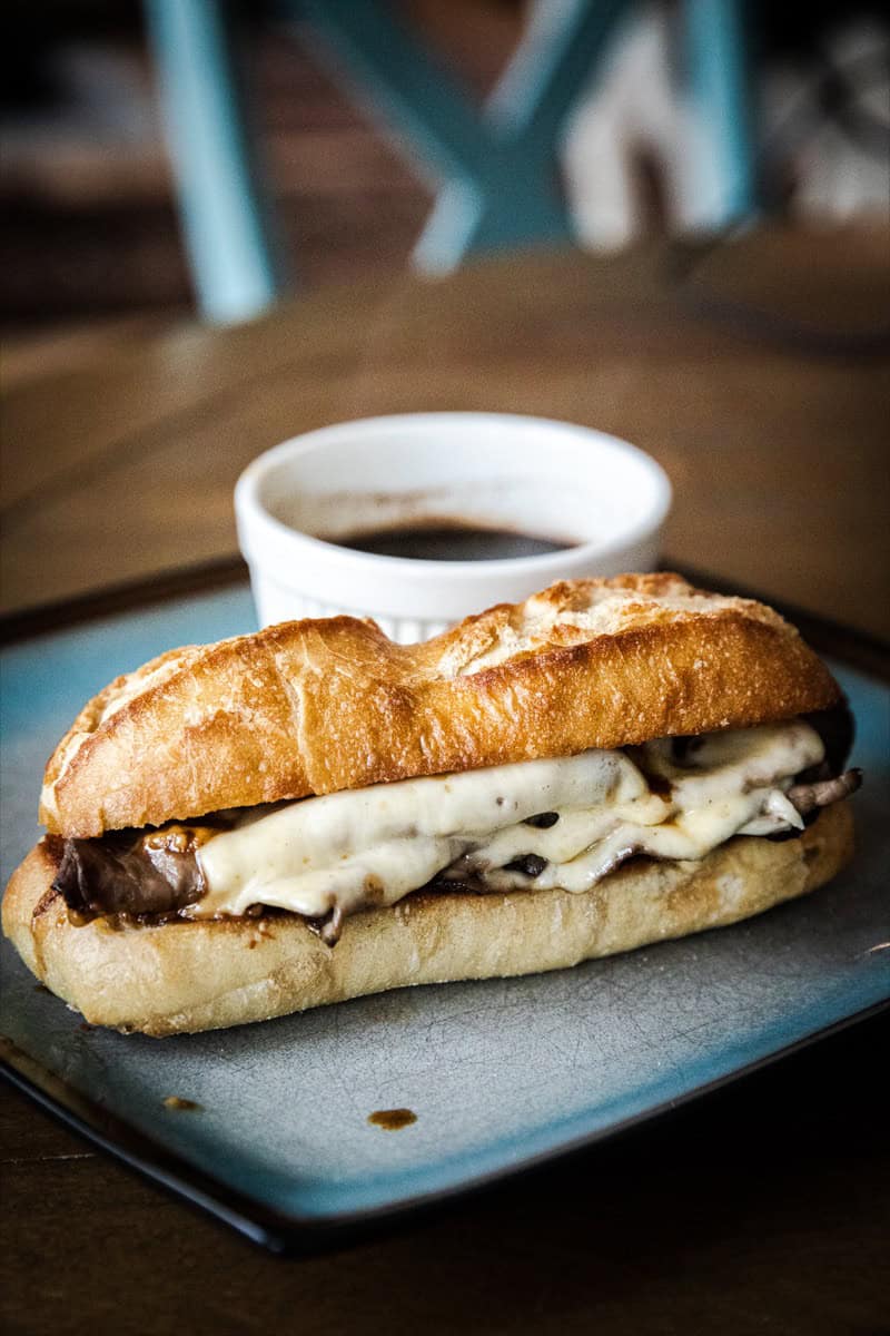 Delicious French Dip sandwich with melted cheese and beef, served with a side of au jus.