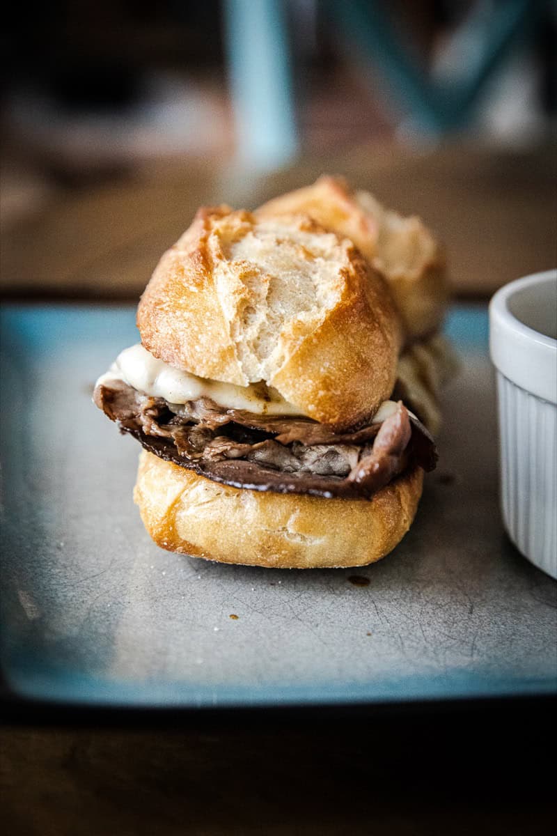 Close-up of a French dip sandwich with beef, au jus, and bread.