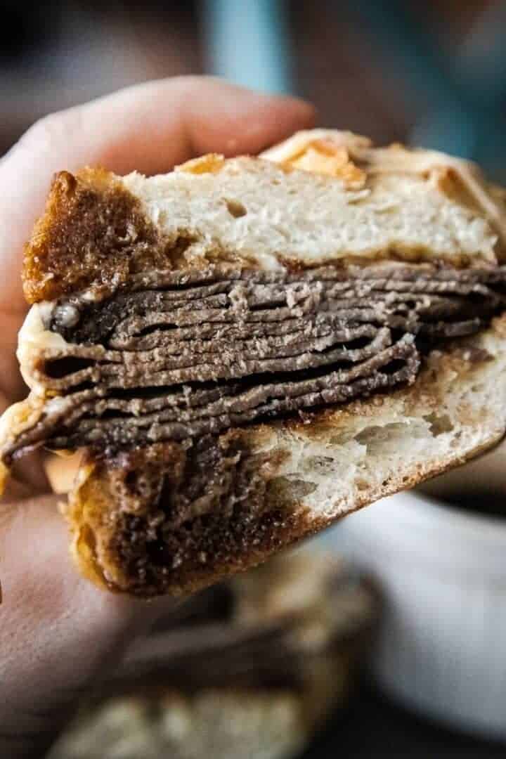 Close-up of a French dip sandwich with beef and bread.
