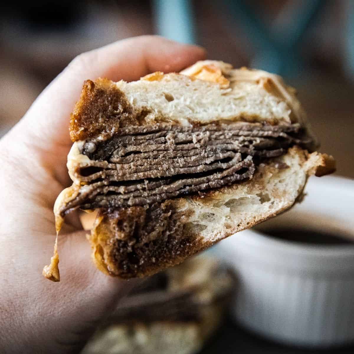 Close-up of a French dip sandwich with beef and bread.