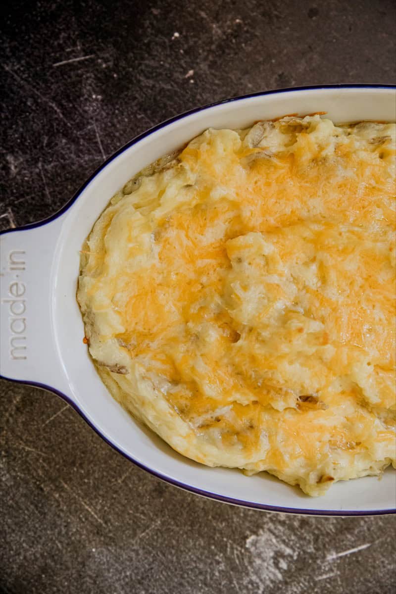 Creamy cheesy mashed potatoes baked to golden perfection in a white dish.