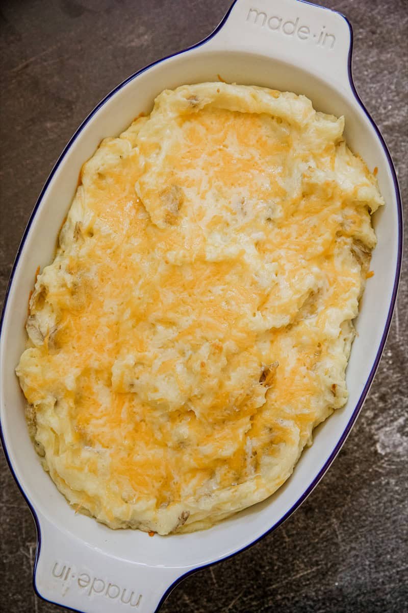 Creamy cheesy mashed potatoes in a white dish, perfect for comfort food.
