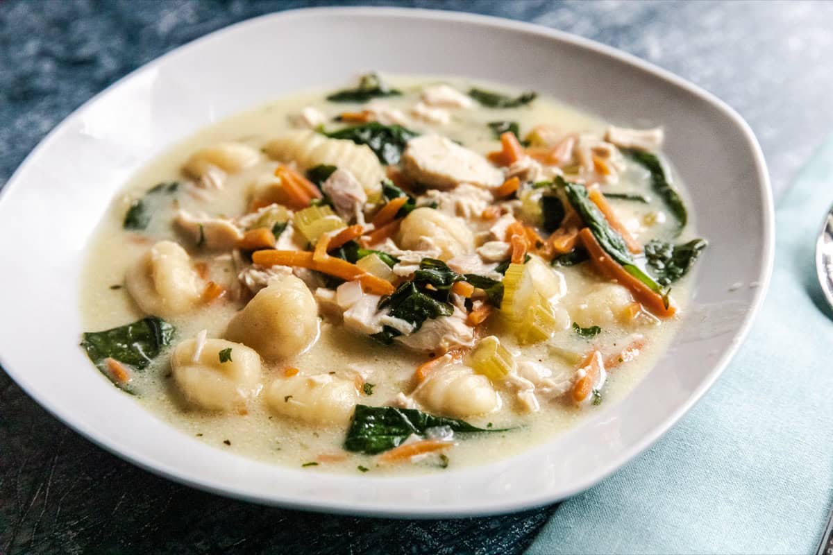 Chicken gnocchi soup in a white bowl with spinach