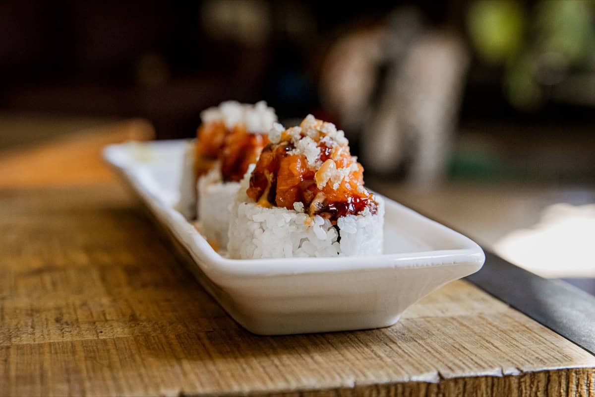 Close-up of spicy dynamite sushi rolls on a white dish.