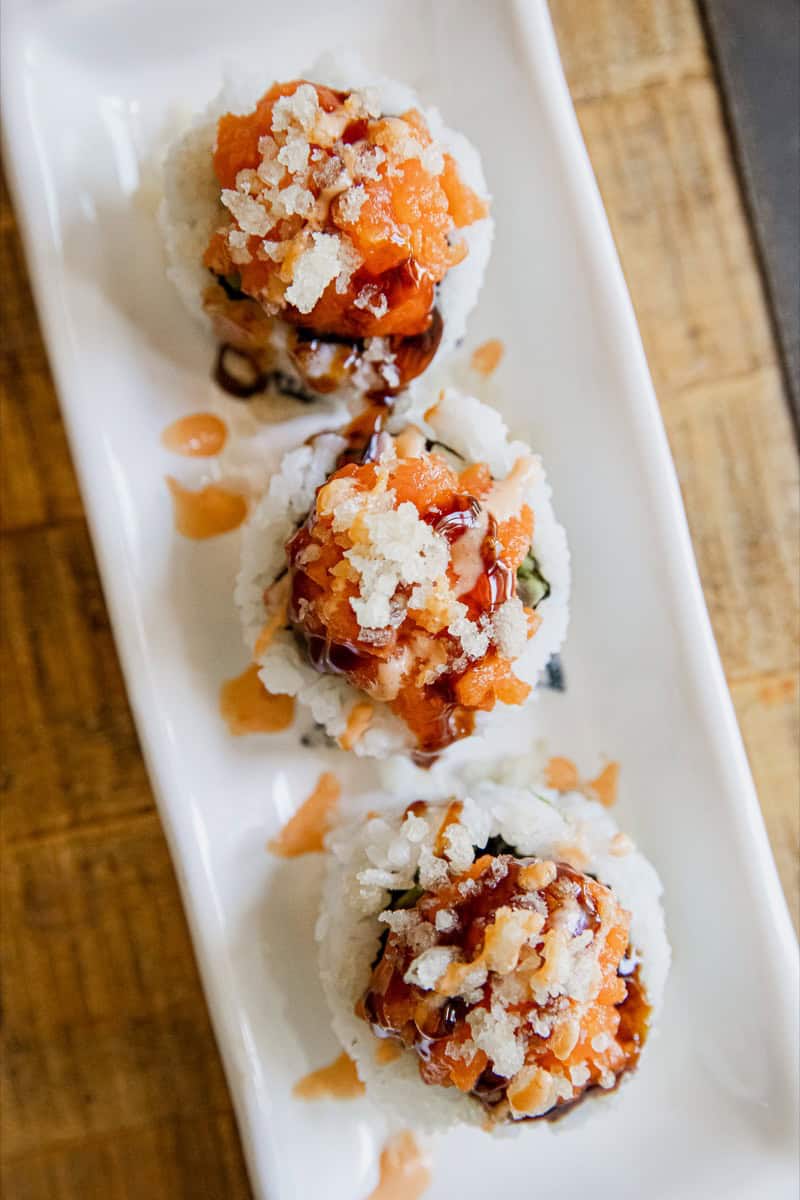 Close-up of spicy dynamite sushi rolls with sauce and toppings.