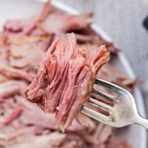 Tender, juicy double smoked picnic ham on a fork, ready to serve.