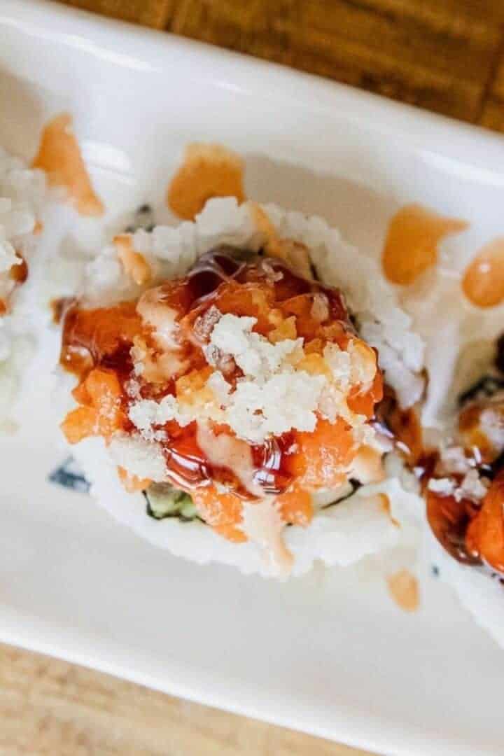 Close-up of spicy dynamite sushi rolls with sauce and toppings.