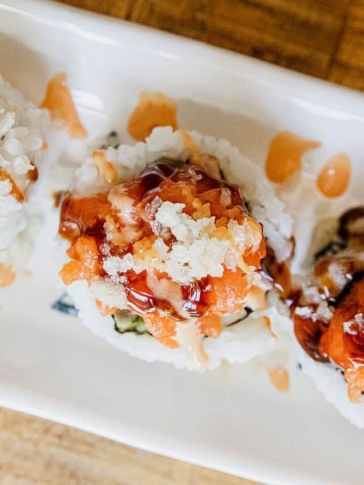 Close-up of spicy dynamite sushi rolls with sauce and toppings.