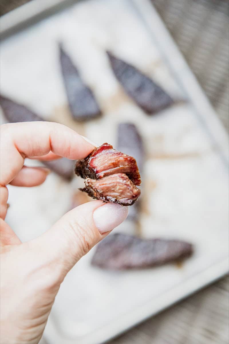 Close-up of smoked boneless chuck short ribs held by hand.