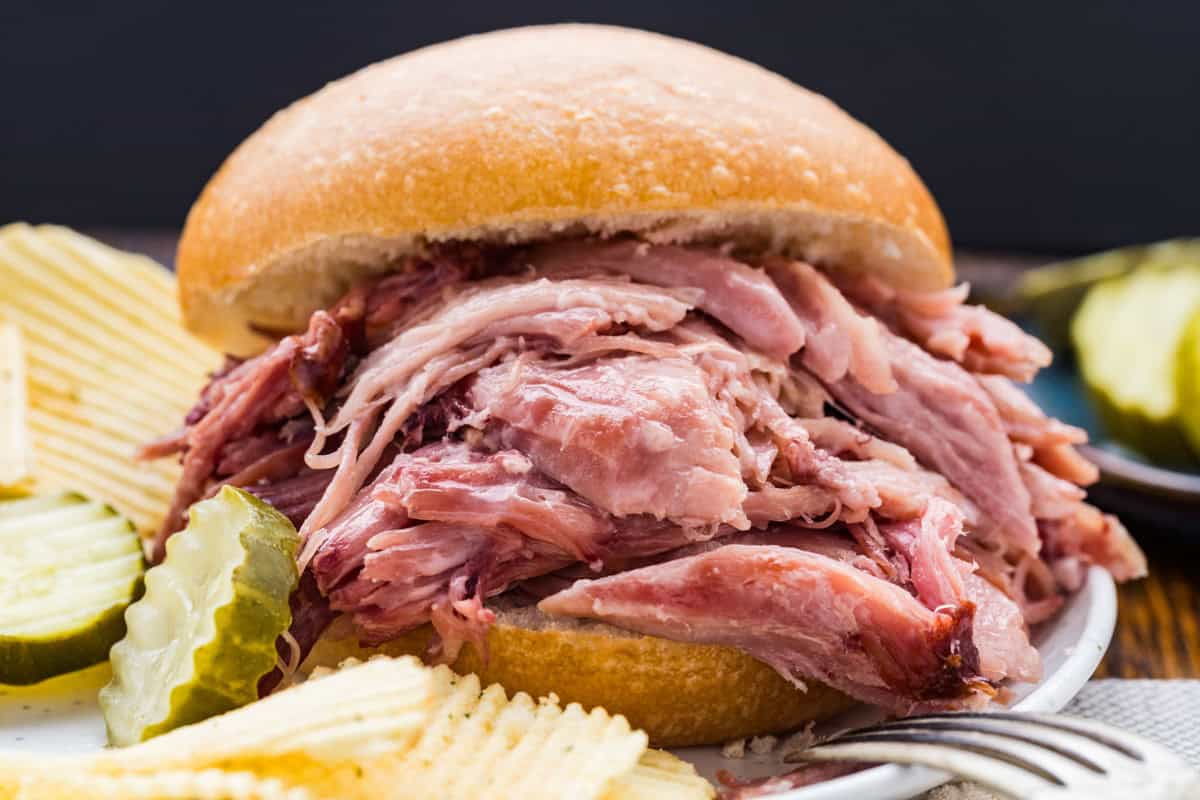 Juicy, tender double smoked picnic ham in a sandwich bun with pickles.