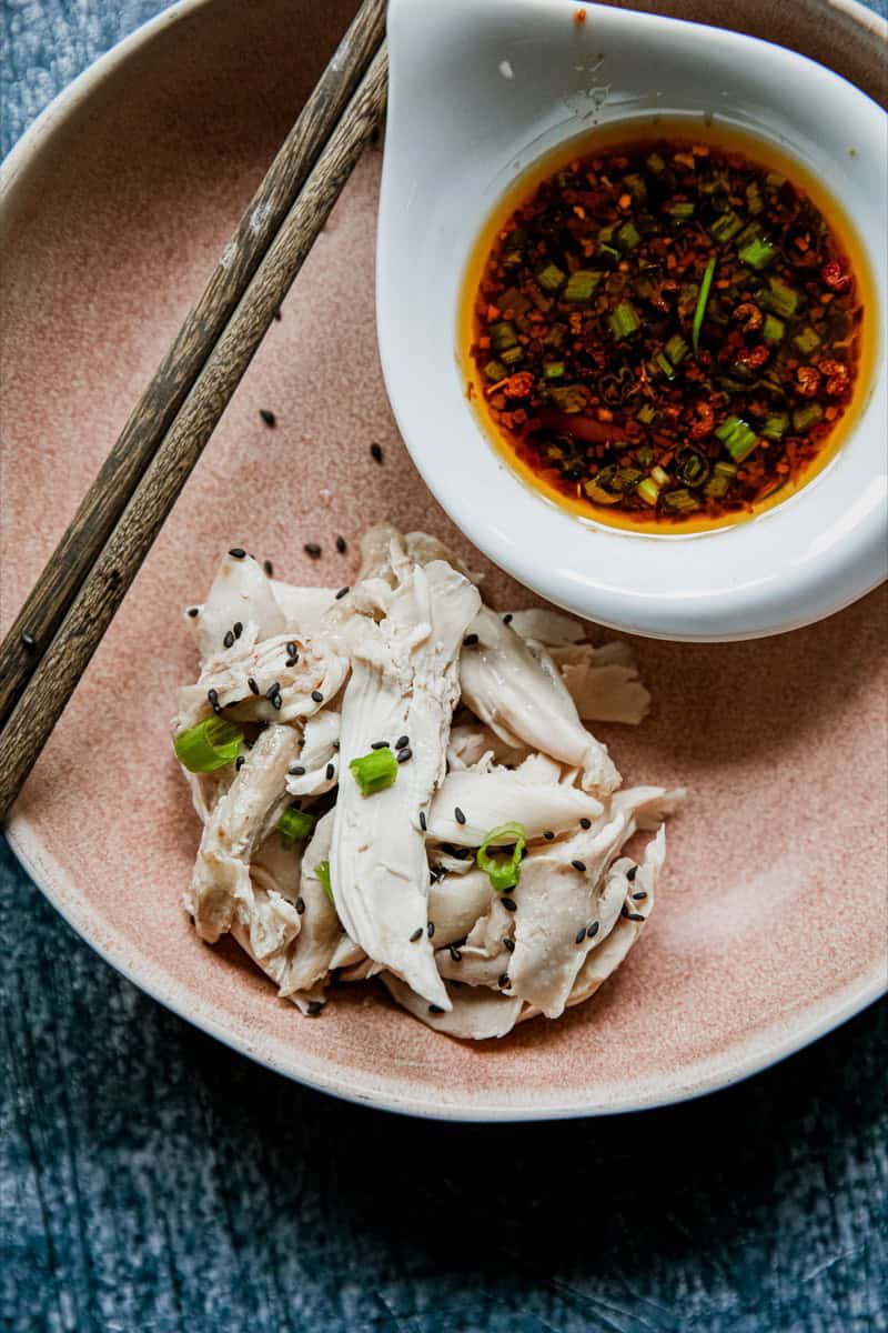 Steamed chicken slices with soy dipping sauce and green onions.