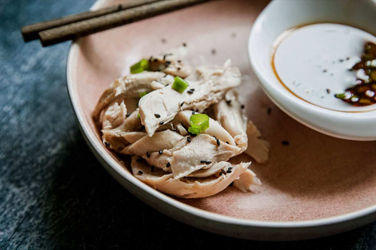 Steamed chicken garnished with green onions served with dipping sauce.
